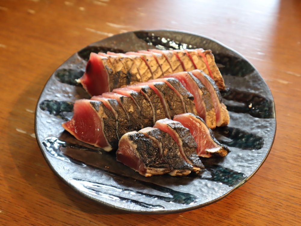 『完全ワラ焼き鰹タタキ「龍馬タタキ」南方上り鰹』が皿に盛られている写真