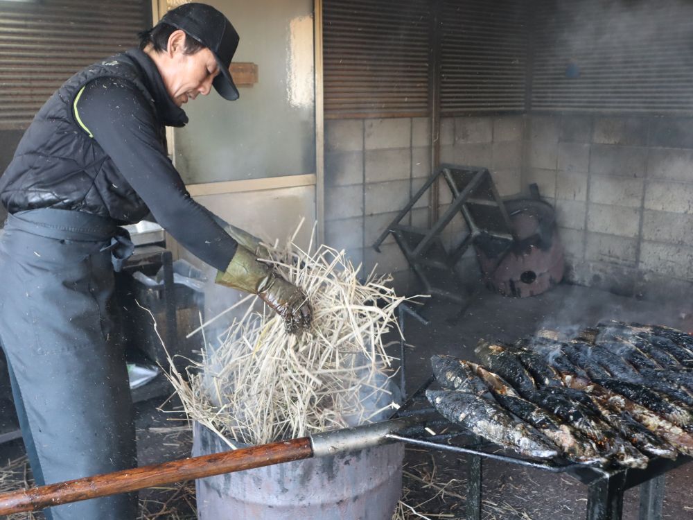 職人がドラム缶にワラを入れ、鰹のタタキを焼いている様子