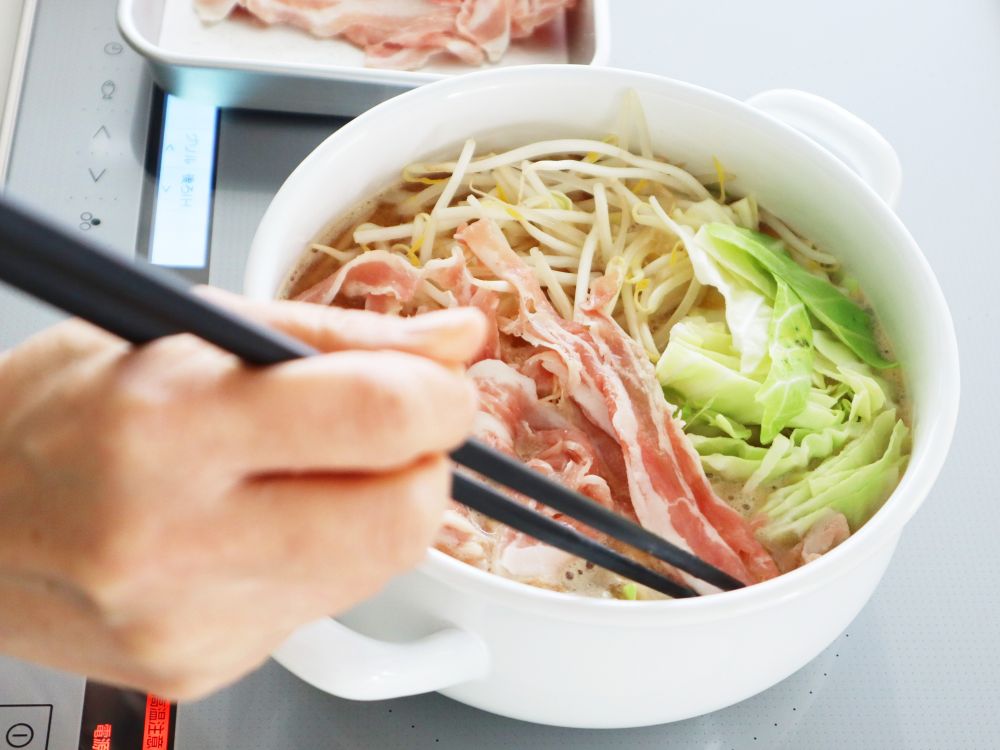 鍋の中に野菜と肉を入れている様子