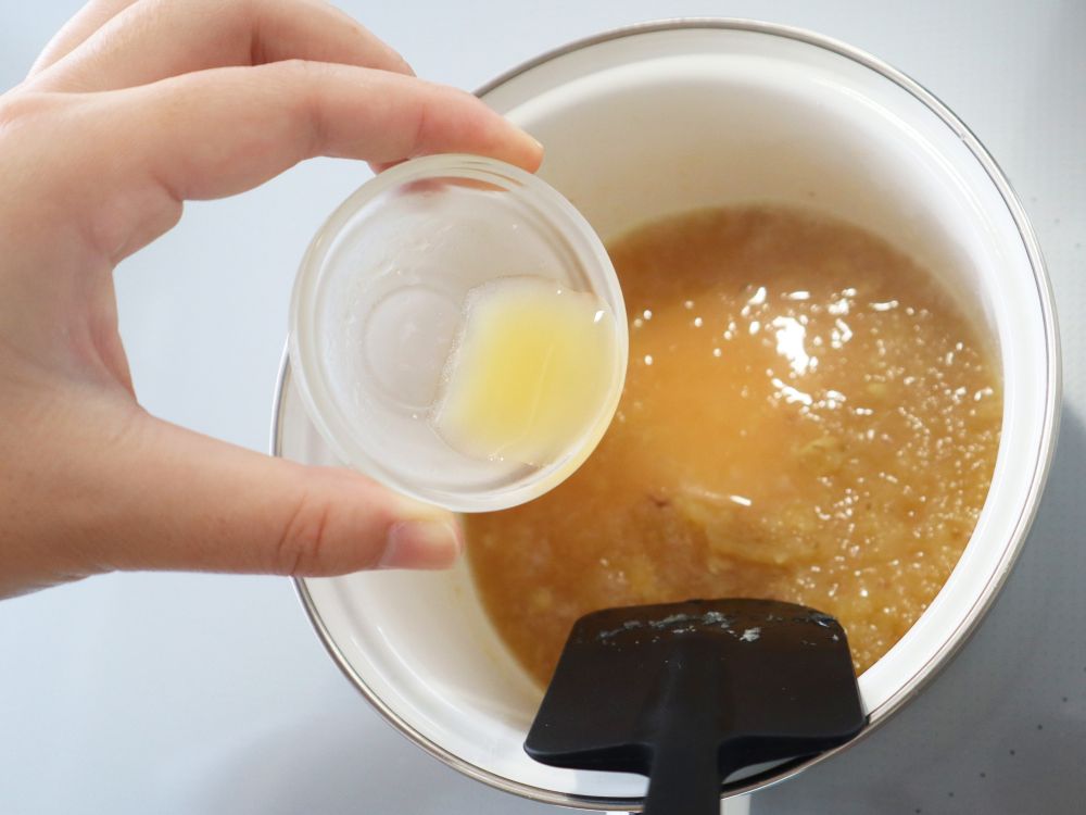 するおろししょうが、砂糖、水を煮詰めた鍋に、レモン果汁を入れている様子