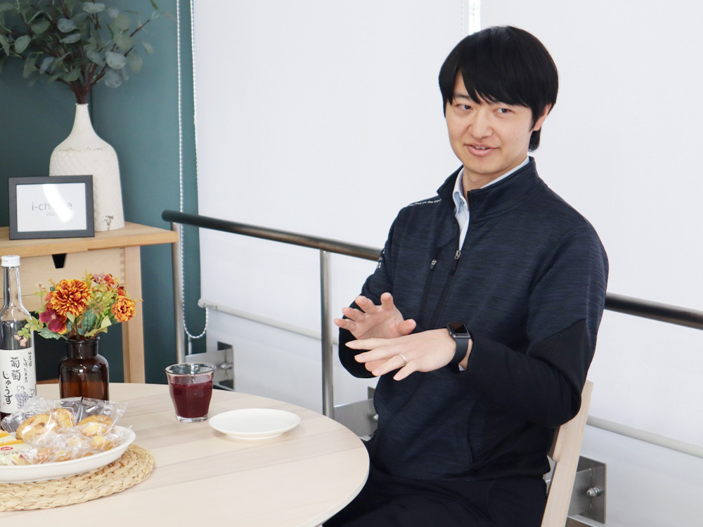 食卓でジェスチャーをまじえながら会話する男性職員Kさん