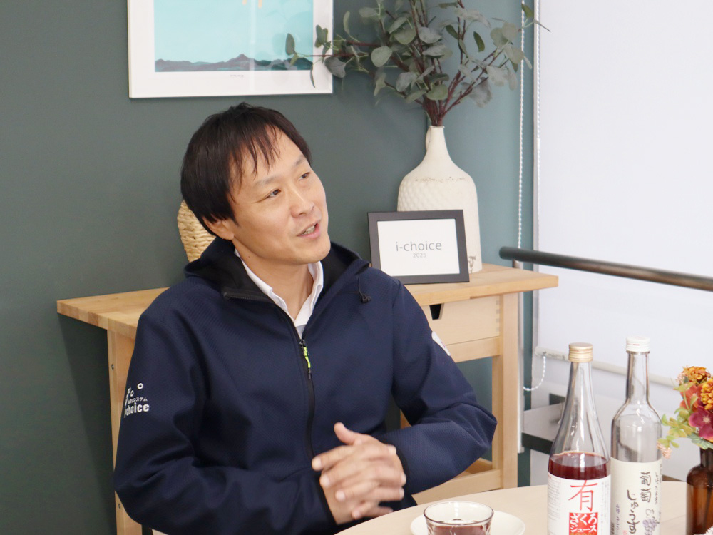 男性職員Mさんが何かを思い出しながら首をかしげているシーン