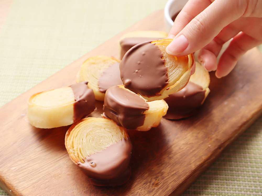 チョコレートソースがつけられて完成した餃子の皮パイのひとつを持ち上げているところ