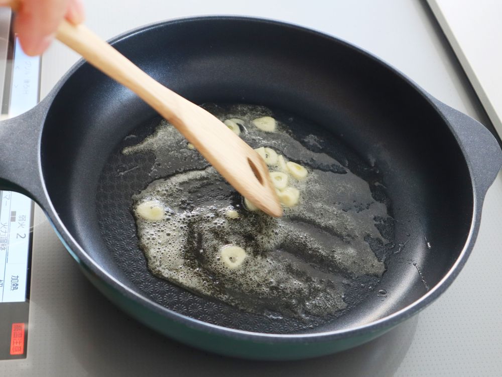 フライパンにバターを溶かしスライスしたにんにくを炒めている写真