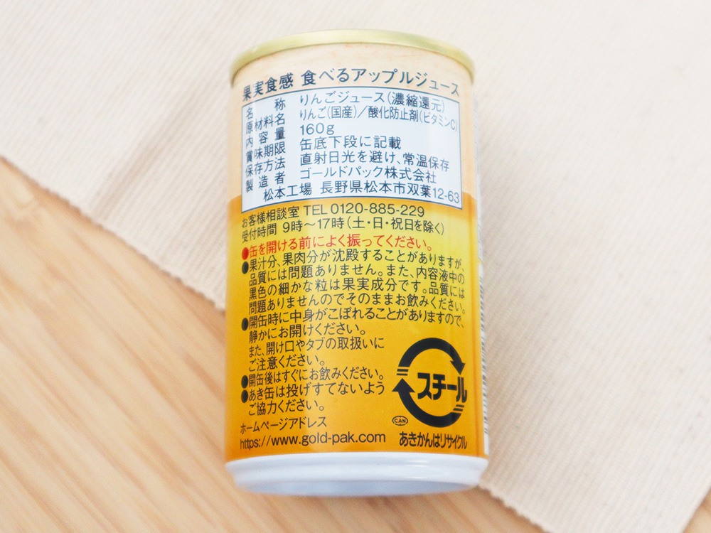 ゴールドパックの商品である『食べるアップルジュース』の缶の裏面の写真。原材料一覧や「缶を開ける前に良く振ってください」等の注意文が確認できる。