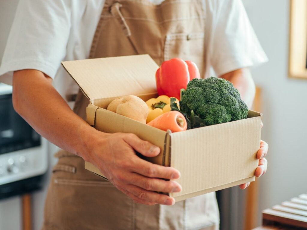 野菜の入った段ボールを抱える男性