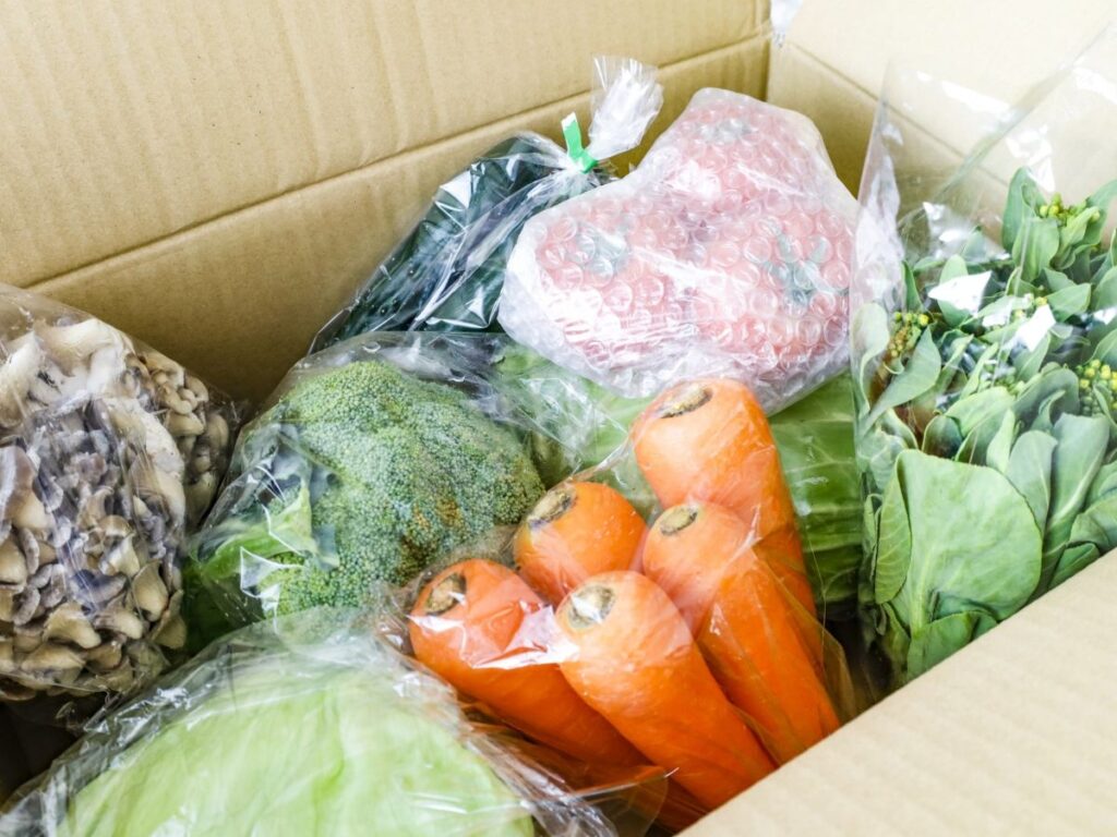 段ボールに袋詰めされた野菜が入っている にんじん トマトなど