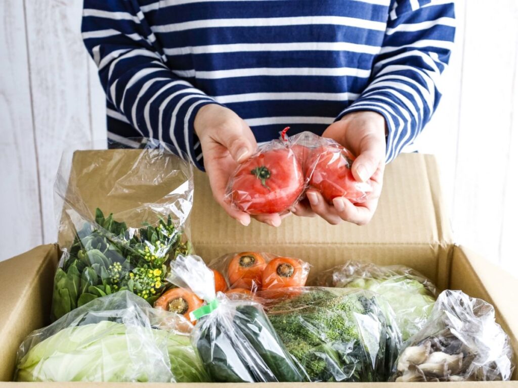 段ボールから袋詰めされたトマトを取り出す女性
