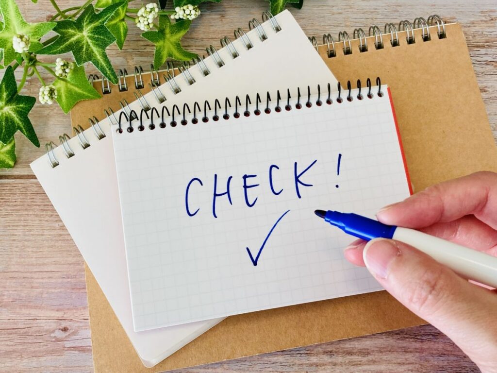 メモ帳に青いペンでチェックと書いた写真