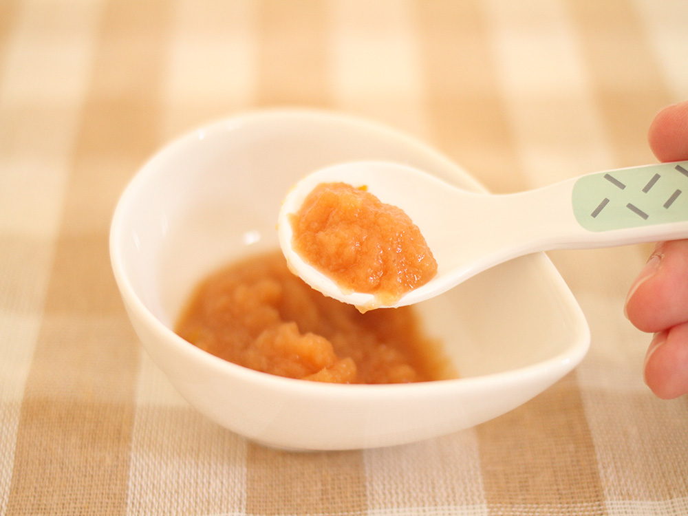 器に入った離乳食をスプーンですくい上げているところ