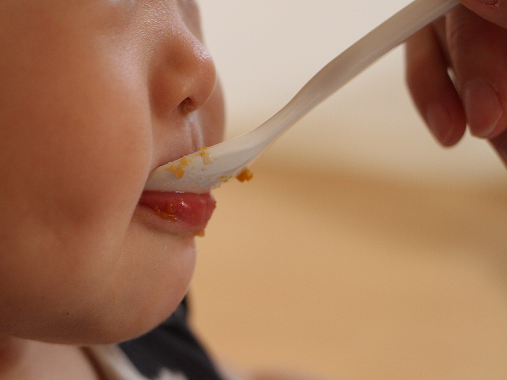 子どもが離乳食を食べさせてもらっているシーン