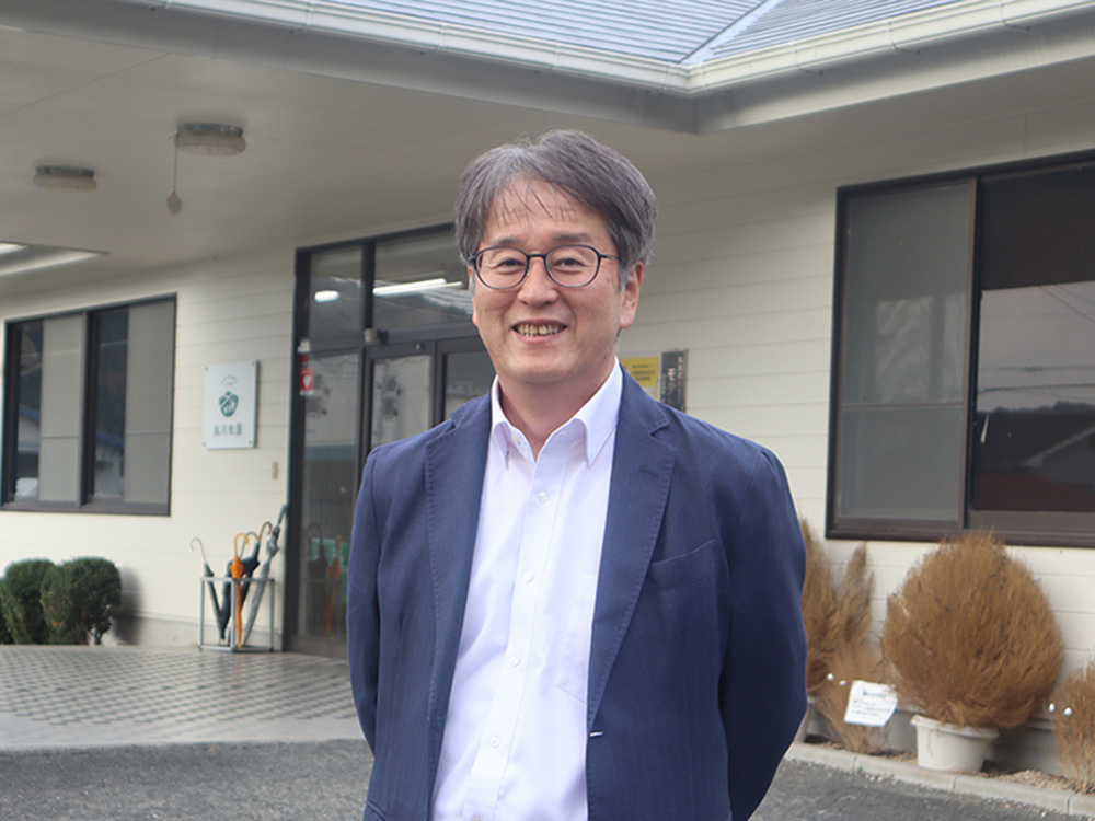 秋川社長（スーツを着た男性）の写真