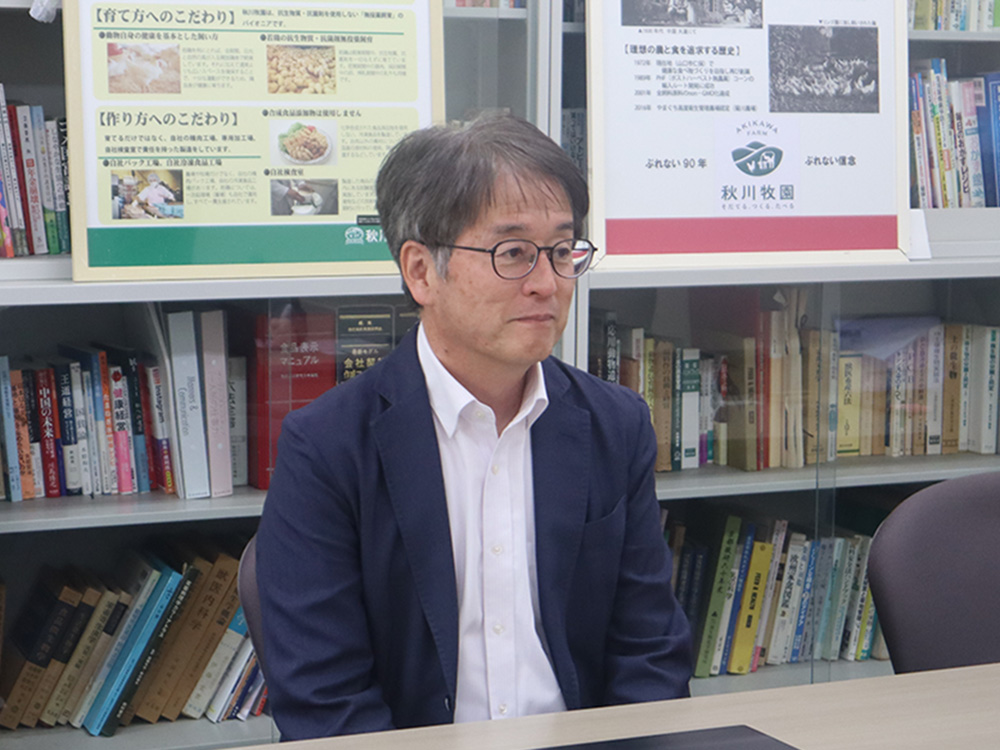 秋川社長(スーツを着ている男性)が机に座って話をしている写真