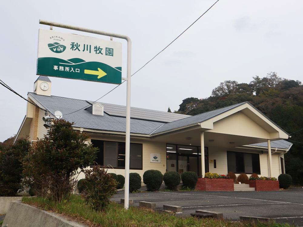 秋川牧園の社屋と入口案内と書かれた看板の写真