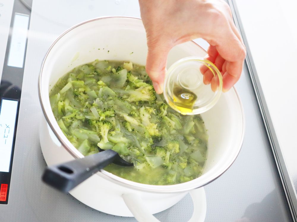 ポタージュの入った鍋にオリーブ油をたらし、仕上げている様子