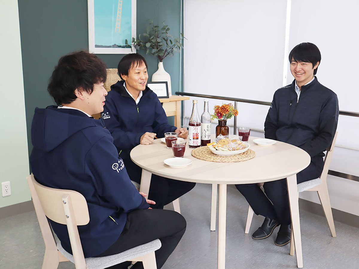 テーブルを囲んで談笑する男性職員3人