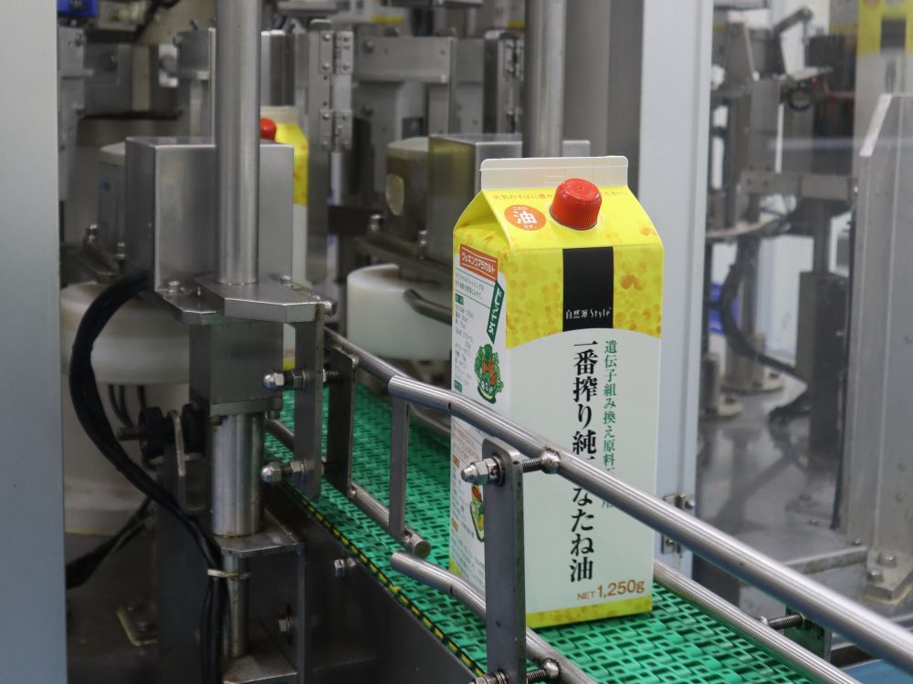 パック詰めされたなたね油がラインに乗って流れてくる様子
