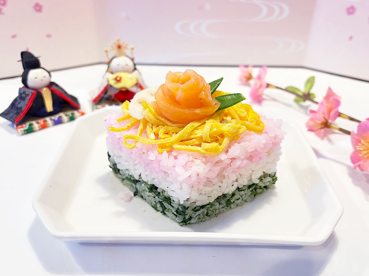 牛乳パックで成形されたちらし寿司にひな人形などが背景に飾られている様子