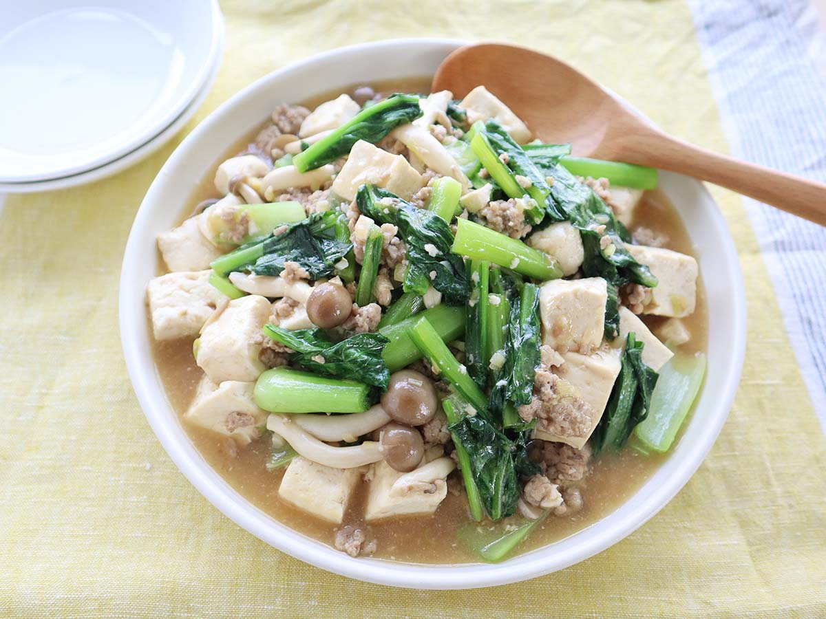 完成した小松菜マーボー豆腐が大皿に盛りつけられ取り分け用スプーンと小皿が添えられている写真