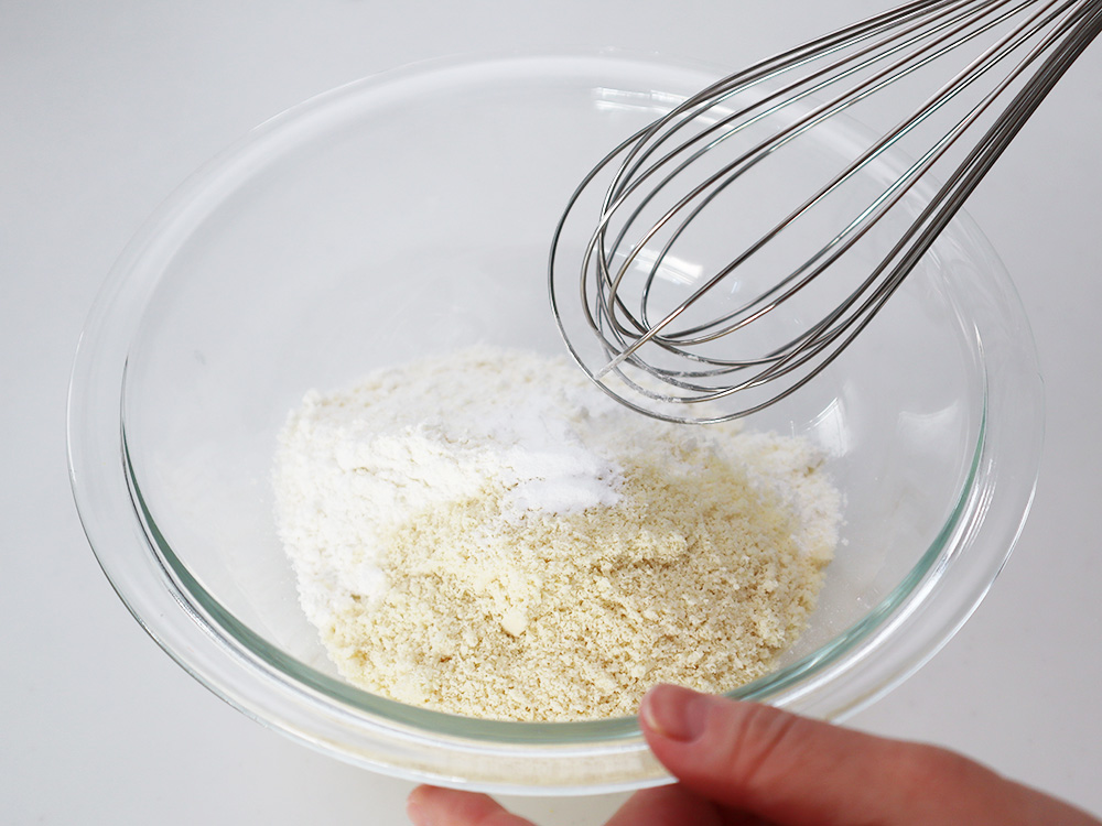 薄力粉、アーモンドプードル、ベーキングパウダーをボウルに入れ、泡だて器でよく混ぜ合わせるところ