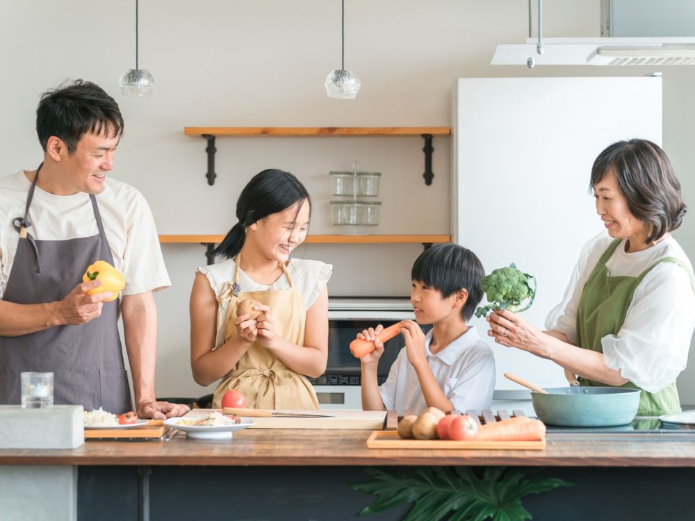 家族でキッチンに立ち料理をする様子