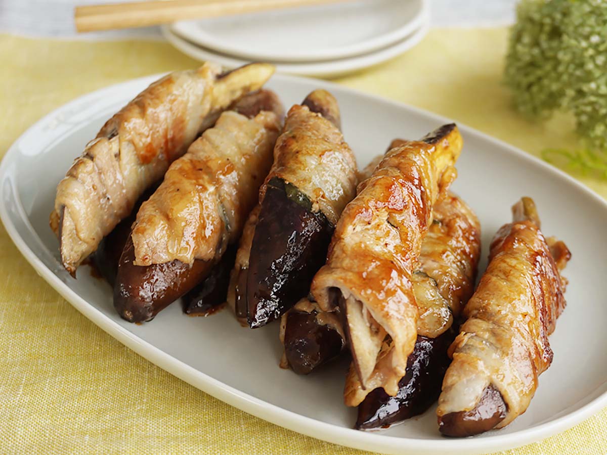 肉巻きなすの照り焼きが楕円の皿に盛りつけられている写真