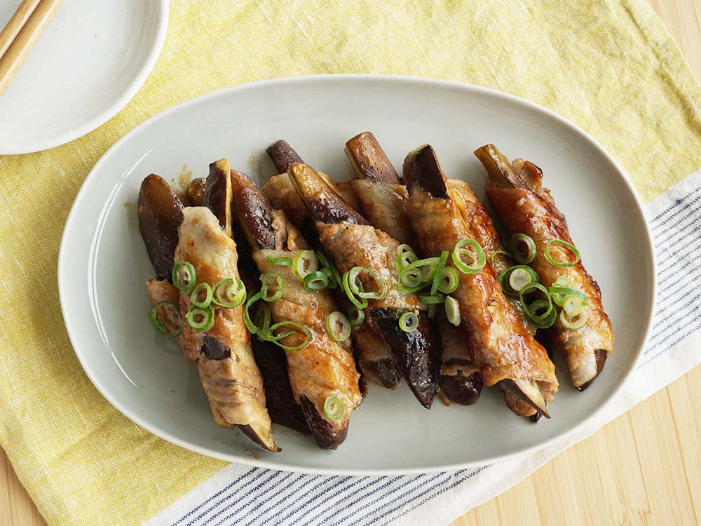 6本の肉巻きなすの照り焼きが楕円の皿に盛りつけられている写真