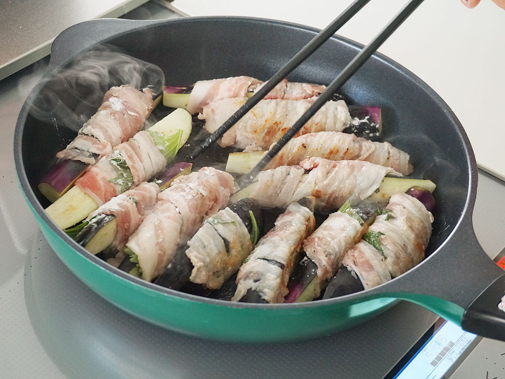 肉巻きなすを菜箸で触りながらフライパンで焼いているシーン